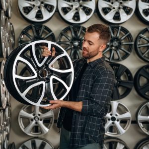 Brand new disk. Man worker is maintenance station with tires, wheels.