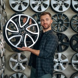Brand new disk. Man worker is maintenance station with tires, wheels.