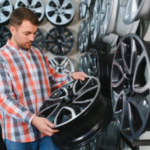 Car mechanic holding car rims ready to mount the wheels in workshop.