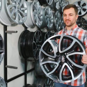 Car mechanic holding car rims ready to mount the wheels in workshop.